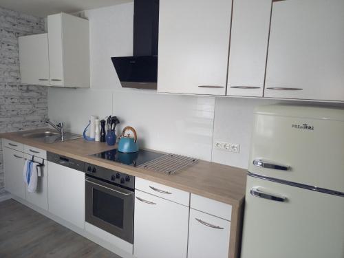 a kitchen with white cabinets and a sink and a refrigerator at FeWo Marie Magdalena in Groß Köris