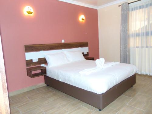 a bedroom with a large bed with white sheets at KILIMANI BREEZE HOTEL in Wote