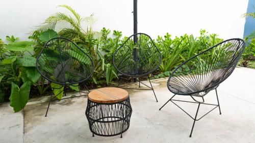 three black chairs and a stool in front of plants at Aldeazul by Andiani Travel in Cancún