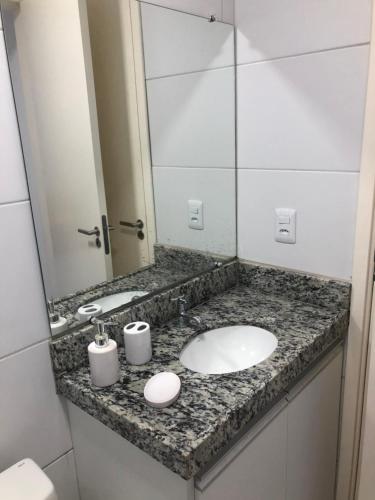 eine Badezimmerablage mit Waschbecken und Spiegel in der Unterkunft Muro alto Condomínio Clube flat 211 in Porto De Galinhas