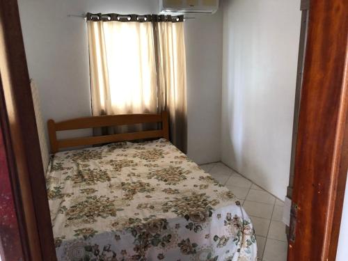 a small bedroom with a bed with a floral bedspread at casa praia em bombinhas in Bombinhas