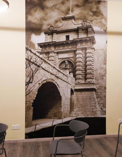 a wall mural of an archway in a room with a chair at Mayflower Hotel Malta in St Paul's Bay