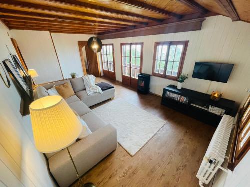 a living room with a couch and a tv at Chalet 4 personnes avec sauna in Leysin