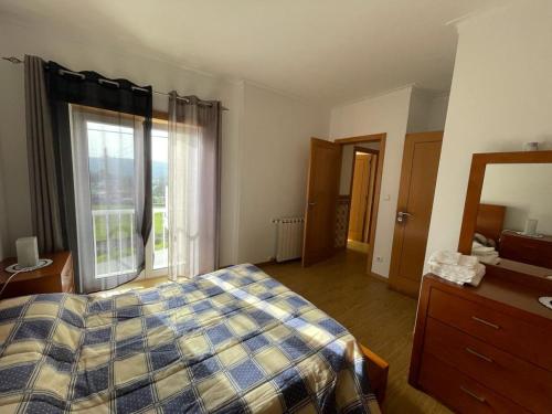 um quarto com uma cama, uma cómoda e uma janela em casa das Termas do Carvalhal em Carvalhal