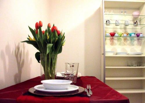 a table with a vase of red tulips on a red table at San Polo Feel The Center in Venice