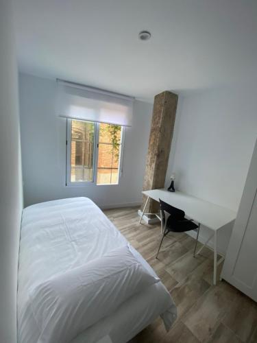 een slaapkamer met een wit bed en een bureau bij Cozy flat in La Petxina B in Valencia