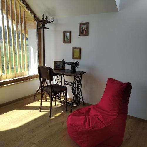 a living room with a table and a red couch at Hiša sonca Toti breg in Svečina