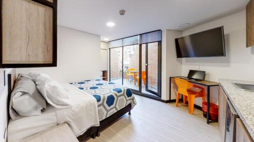 Dormitorio con cama, escritorio y TV en Terrazas en Bogotá