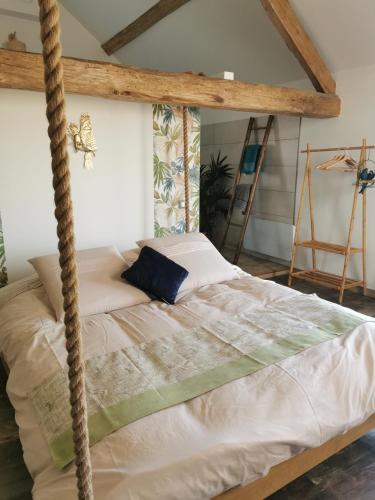 een bed in een kamer met een touwschommel bij La bulle suspendue in Bassevelle