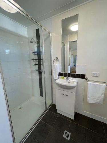 a white bathroom with a shower and a sink at Fishing Haven Holiday Park in Palmers Island