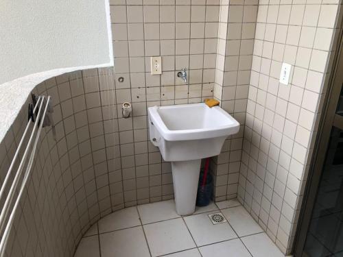 a bathroom with a white sink in a tiled room at apartamento bombinhas in Bombinhas