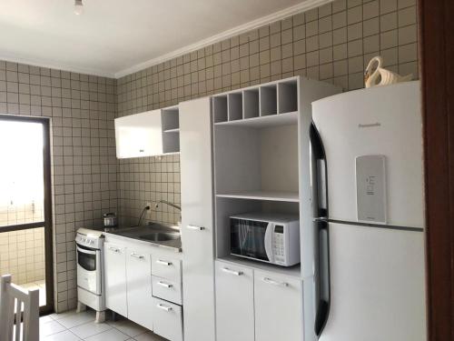 a kitchen with a white refrigerator and a microwave at apartamento bombinhas in Bombinhas