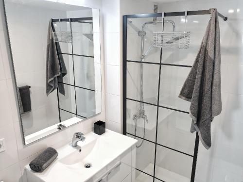 a white bathroom with a shower and a sink at Tamaran 106 Vv Maspalomas in Playa del Ingles