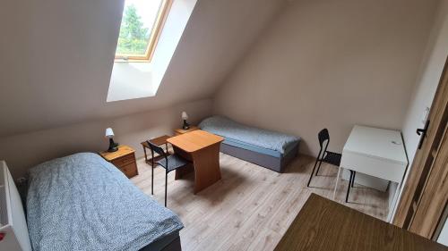 a room with two beds and a table and a desk at W20 Hostel in Golędzinów