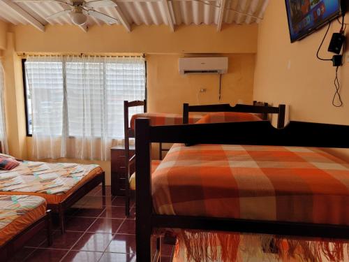 a bedroom with two beds and a tv and a window at Hostal Haziel in Salinas