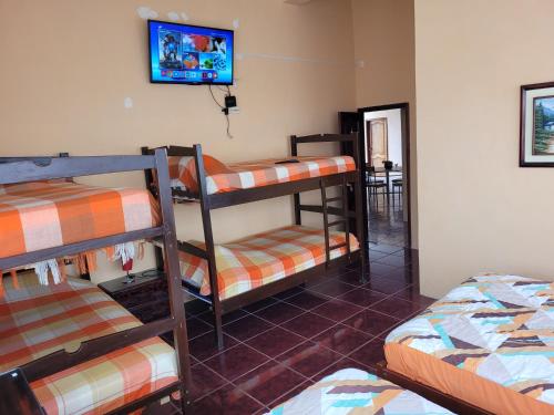 a room with three bunk beds and a tv on the wall at Hostal Haziel in Salinas