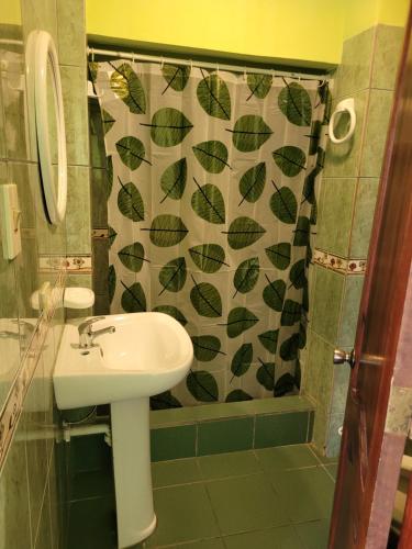 baño con lavabo y cortina de ducha con hojas en Hostal Haziel, en Salinas
