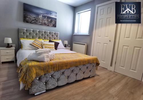 a bedroom with a large bed with a yellow blanket at Spireview 2 Bedroom Apartment EVB Properties Short Lets & Serviced Accommodation ,Titanic City- Southampton in Southampton