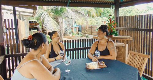 three women sitting at a table with wine glasses at KIA ORA Lodge in Afaahiti