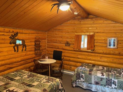 a bedroom with two beds and a table in a cabin at Carlo Creek Cabins in McKinley Park