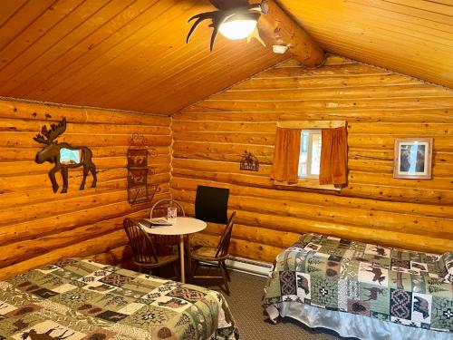 a bedroom with two beds and a table in a cabin at Carlo Creek Cabins in McKinley Park