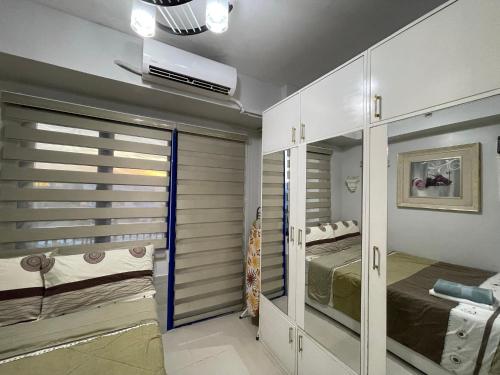 a room with two beds and a closet with mirrors at Sea Residences MoA Manila in Manila