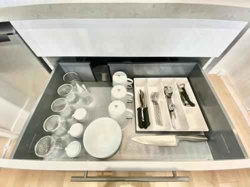 un tiroir rempli de vaisselle et d'ustensiles dans l'établissement ModernAppart Marmande Centre, à Marmande