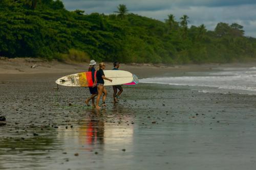 two people walking on the beach with their surfboards at Bungalows Ballena in Uvita