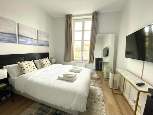 una camera da letto con un letto bianco e asciugamani di StandingHouse Marmande Centre a Marmande