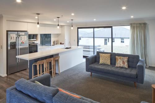 a living room with two couches and a kitchen at Loudon Lodge - Lake Tekapo in Lake Tekapo
