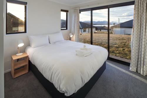 um quarto com uma cama grande e uma janela grande em Loudon Lodge - Lake Tekapo em Lake Tekapo