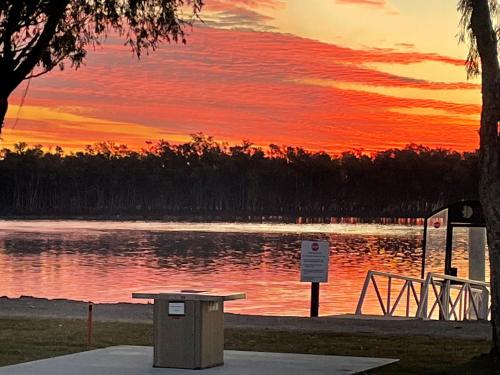 a sunset over a body of water with a trash can at Fishing Haven Holiday Park in Palmers Island