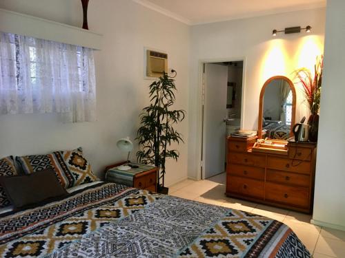 Schlafzimmer mit einem Bett, einer Kommode und einem Spiegel in der Unterkunft Palmerston Sunset Retreat in Palmerston