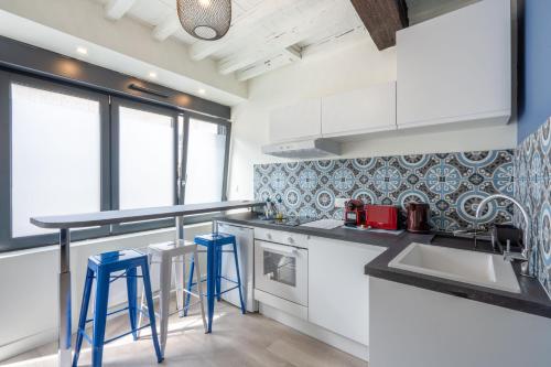 une cuisine avec des placards blancs et des tabourets bleus dans l'établissement La WAIDE Beau studio centre ville WIFI NETFLIX tout équipé, à Amiens