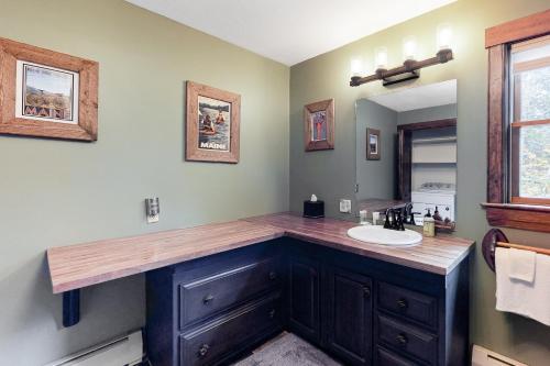 a bathroom with a counter with a sink and a mirror at Sunday River Ski House in Newry