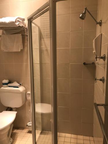 a bathroom with a shower and a toilet at Country Plaza Motel in Queanbeyan