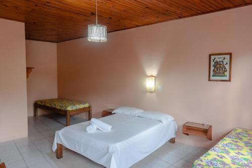a bedroom with a bed and a table and a chair at Alecrim Pousada in Praia do Rosa