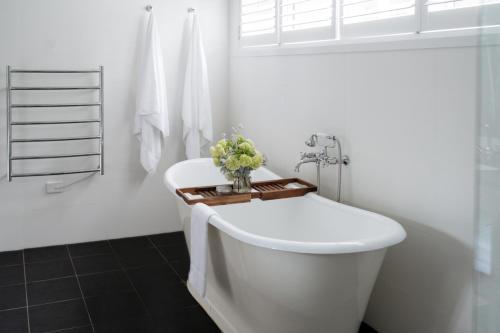 a white bathroom with a tub and a sink at Bells at Killcare Boutique Hotel, Restaurant & Spa in Killcare