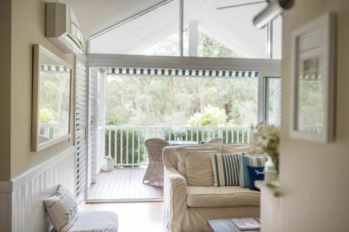 a screened in porch with a couch and a chair at Bells at Killcare Boutique Hotel, Restaurant & Spa in Killcare