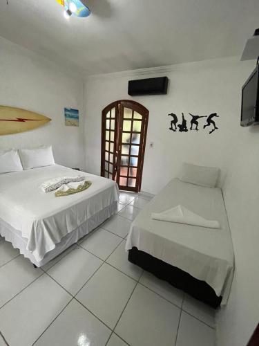 a bedroom with two beds and a television in it at Pousada Praia do Tombo in Guarujá