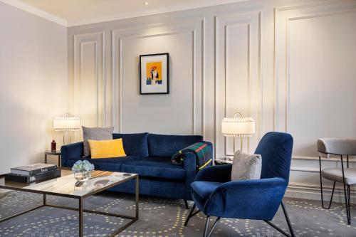 a living room with a blue couch and chairs at Fable Dunedin in Dunedin