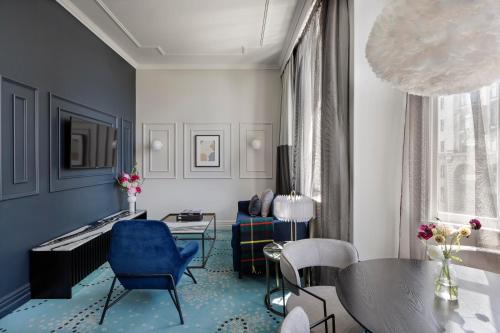 a living room with a table and blue chairs at Fable Dunedin in Dunedin
