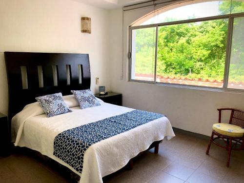 1 dormitorio con 1 cama grande y ventana grande en Casa Romantica De Playa, en Ixtapa