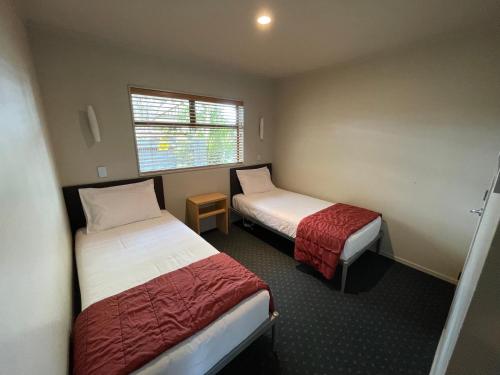 a small room with two beds and a window at Bentleys Motor Inn in Palmerston North