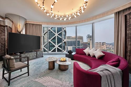 a living room with a red couch and a large window at City of Dreams Macau - Nüwa Macau in Macau
