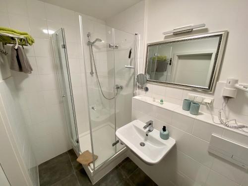 a bathroom with a shower, sink, and mirror at Bärliner Hotel in Erfurt