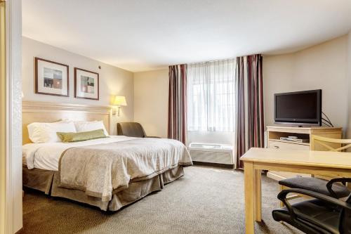 a hotel room with a bed and a flat screen tv at Candlewood Suites Paducah by IHG in Paducah