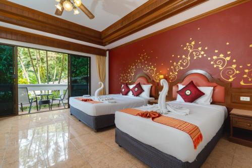 two beds in a hotel room with two swans on the wall at Memory Karon Resort in Karon Beach