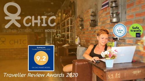 a woman sitting at a table with a laptop at OK CHIC PHUKET HOSTEL in Phuket Town