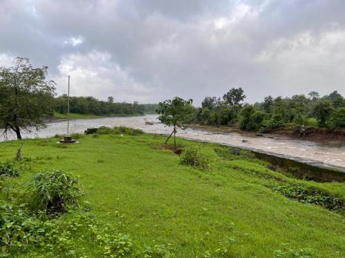 a river with a grassy field next to a river at Karjat Villa (3 BHK) With Garden Amidst Nature in Karjat